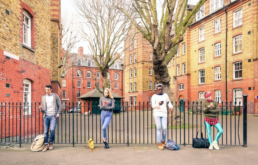 Multiracial people group and urban friends using smartphone near Shoreditch London